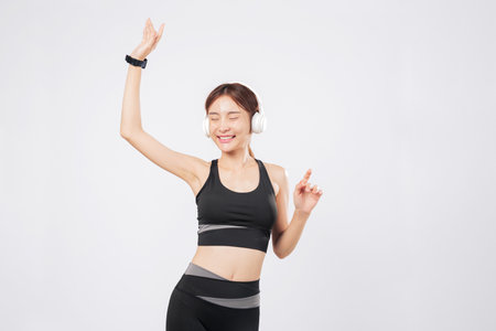 Dance flows naturally when this fit young woman hears her favorite song. Music surrounds her as she pauses, then begins to dance again, strong and full of life. isolated studio white backgroundの写真素材