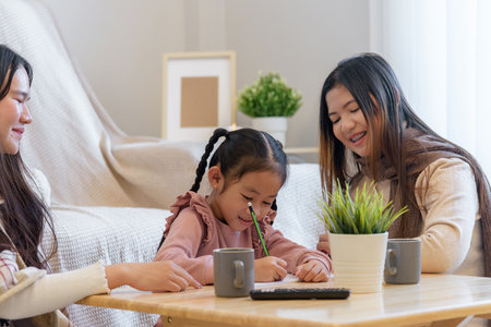 During a warm winter day a child enjoys drawing while sitting with two adults at a table with beverages and a plant, showcasing a moment of creativity and connection indoors.の写真素材