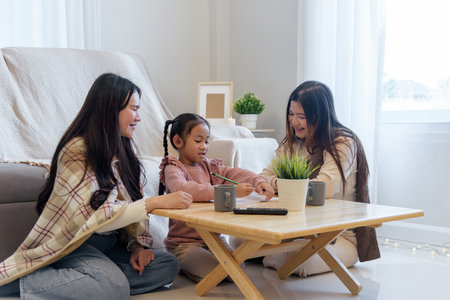 During a peaceful winter day a family enjoys time together indoors as a mother and aunt help a child draw at a low table in a warm cozy and brightly lit room.の写真素材