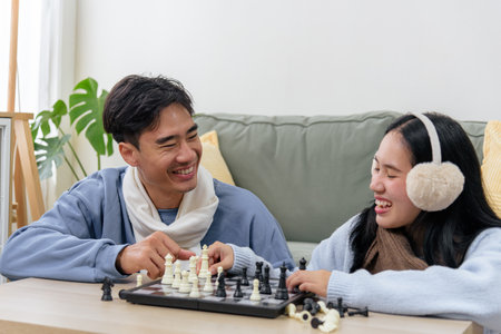 Winter couple, happy people enjoying home indoor time playing lively chess game, sharing genuine...