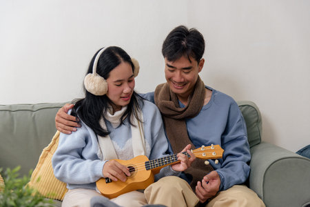 Winter offers happy couple family home indoor moments, young people enjoy warm relaxing time playing ukulele, comfortable clothing for perfect winter comfort and bonding.の写真素材