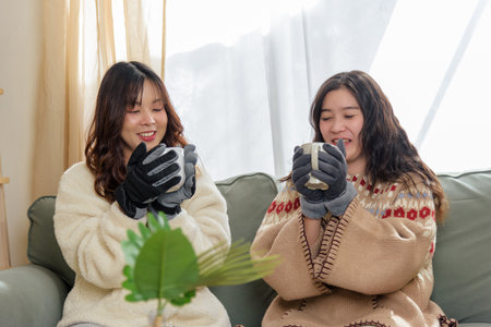 Winter day, smiling women friends at home enjoying warm beverages, cozy friendship brings women...