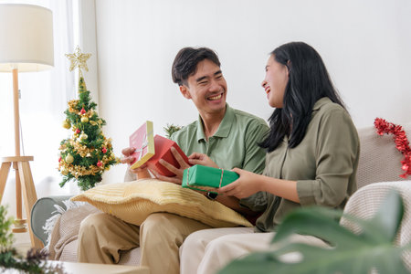 Christmas, happy couple shows love on holiday, opening gifts near festive tree in cozy home, celebrating winter season joyfully, sharing special christmas moment, enjoying cheerful holiday time.の写真素材