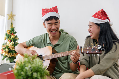 Christmas couple shares love, happy holiday winter moment with music as man plays guitar for woman...