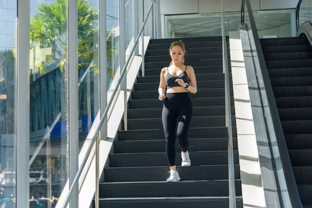 Fit woman performing sport exercise, workout outdoor, descending stairs, healthy living, achieving...