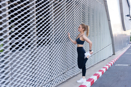 Outdoor workout for fit sport woman, people exercise body stretching, preparing for intense fitness workout against modern urban background, promoting healthy lifestyle.の写真素材