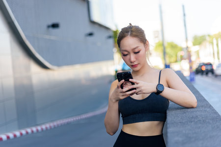 Woman sport exercise workout fit outdoor people ready to stretch, she checks phone for fitness plan after completing light body stretch and warm up.の写真素材