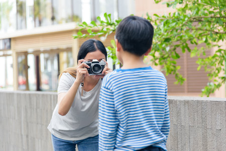 Mother and son, family people, enjoy summer city street activity, woman photographs child with vintage camera, capturing urban outdoor moments, creating happy memories during warm weather fun.の写真素材