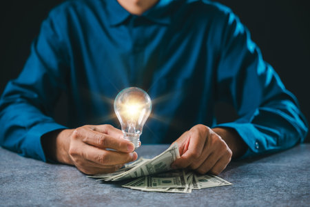 Glowing light bulb idea for business innovation and growth concept, businessman counting currency bank notes on table shows financial success and global marketing management.の写真素材