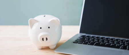 piggy bank for e learning internet education financial online money elearning sits on desk near laptop computer, helping students budget for remote studies and university courses.の写真素材