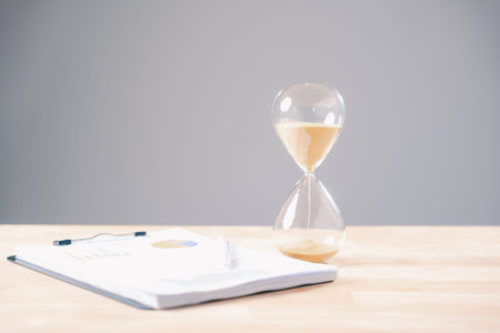 Hourglass pouring sand emphasizes urgent business work, management of essential documents and...
