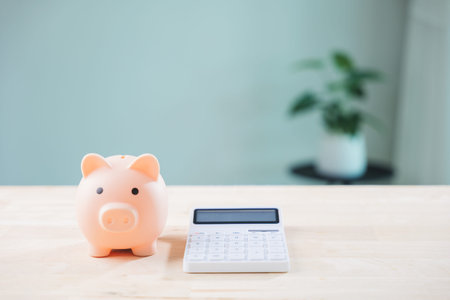 Taxation compliance penalty bank salary transparency money save tax piggy bank beside white calculator illustrates considerations for legal accounting on light wooden table surface.の写真素材