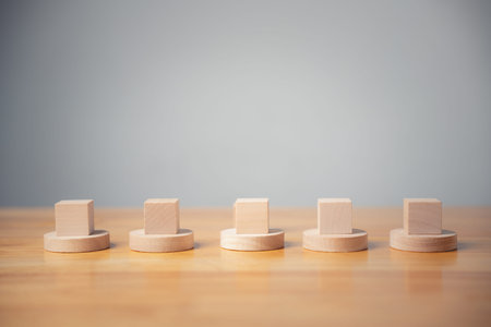 Five wooden blocks on round bases, arranged in a line on a wooden table.  Minimalist, clean, and...