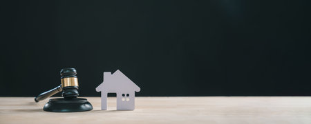 Foreclosure house real estate law concept displayed with wooden judge gavel next to small paper home cutout symbolizing property auction mortgage debt legal sale decision for buyers attorney.の写真素材