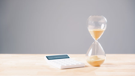 Hourglass shows time passing, sandglass symbolizes important tax deadline, calculator for business...