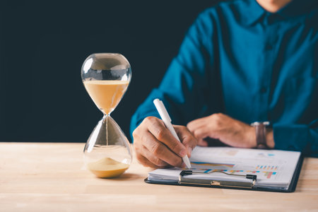 Hourglass sand measuring time for business document management, busy financial job under strict...