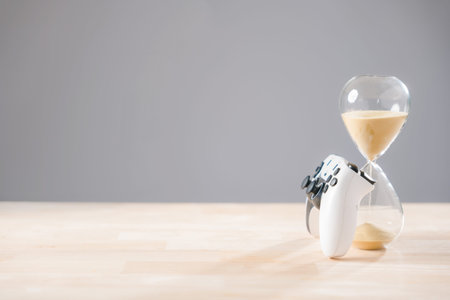 Gaming controller and hourglass visually represent time management for playtime, sandglass measures...