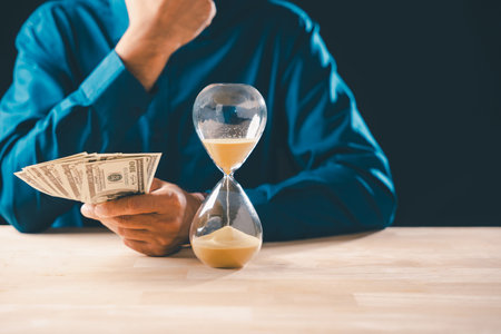 Person holding money banknotes, time hourglass visually represents global business investment...