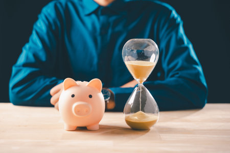 Person considers time money concept with hourglass and piggy bank, emphasizing finance saving for...