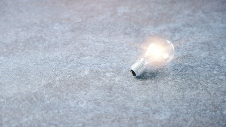 Lightbulb bulb light idea concept creative innovation business design radiates on grey stone surface...