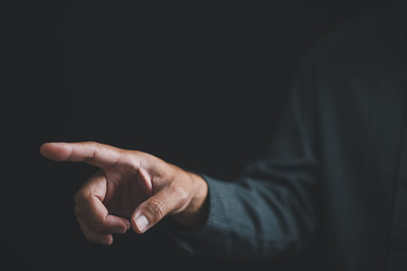 Close-up of a hand reaching out against a black background, with fingers extended.