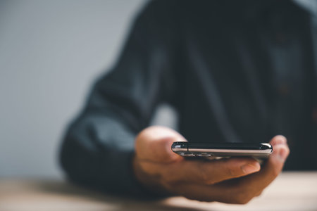 Close-up of a hand holding a smartphone with a blurred background.