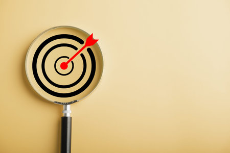 A magnifier glass focusing on target board, reflecting the dedication to hit business objectives. Against background with copy space, it symbolizes the pursuit of success and the art of strategic aim