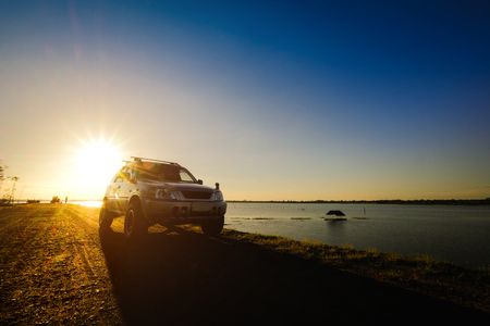Businessmen with SUV cars parked on the dirt road along the reservoir. Watching the sunsetの写真素材