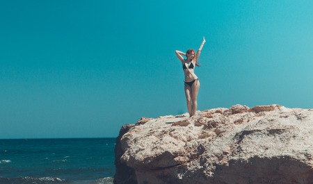 young girl in black bikini standing at Rock near sea, crete, Greece, portraitの写真素材