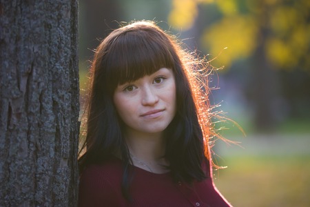 Portrait of Pregnant woman standing in autumn park at sunset and looking to camera, close upの写真素材
