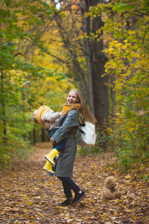 Happy family have fun walking in autumn park - The mother playing with her daughter among the yellow leaves, telephotoの写真素材