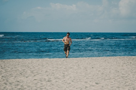 Young man having jogging at the beach on tropical resort, Dominican republicの写真素材