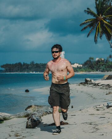 Young man having jogging at the beach on tropical resort, telephoto, Dominican republicの写真素材