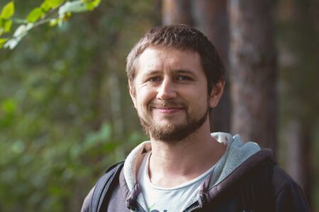 Adult strong man with beard smiling in forest, portraitの写真素材