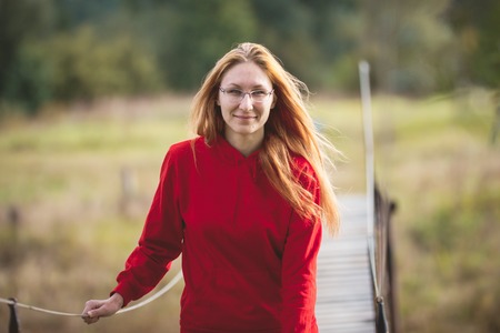 Portrait of the young beautiful red hair woman in a red coat walking in park, telephotoの写真素材