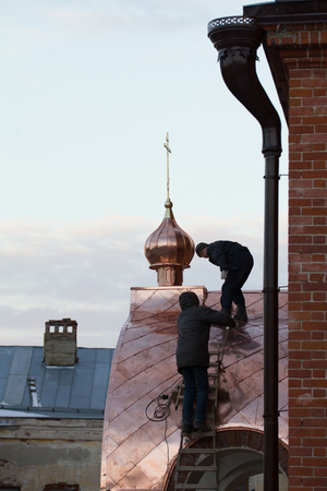 KAZAN, RUSSIA, 19 NOVEMBER 2016, two workers Roofer repairing roof of ortodox Old believers ' Church in winter cold day, horizontalのeditorial素材