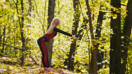 Girl having a training work-out in the autumn park. Sexy fitness-bikini blonde model in red suit and pink sneakers, telephotoの写真素材