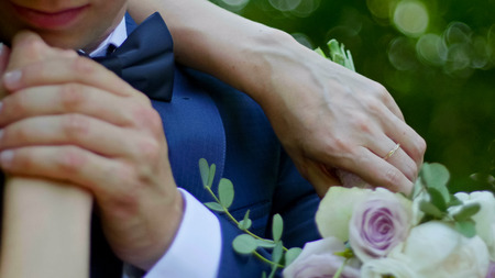 Beautiful bride and groom are kissing in a sunny park, close up, rack focusの写真素材