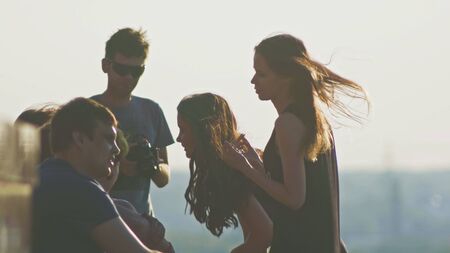 Happy young attractive group of friends having fun and looks at wedding dress together outdoors on a summer day slow-motionの写真素材