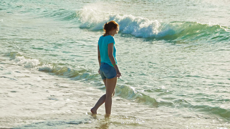 Young woman with long red hair jump and play with sea waves, seascape beach of Dominican Republic,...