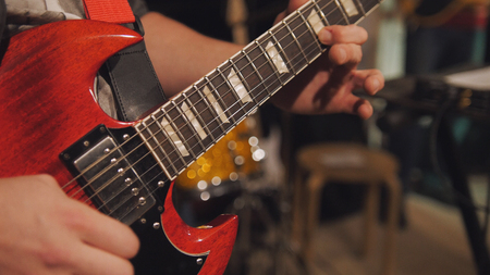 Close up view of guitarist plays electro guitar in night club, telephotoの写真素材