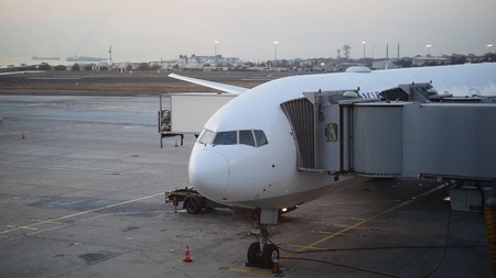 The plane is near the terminal in the international airport at duskの写真素材