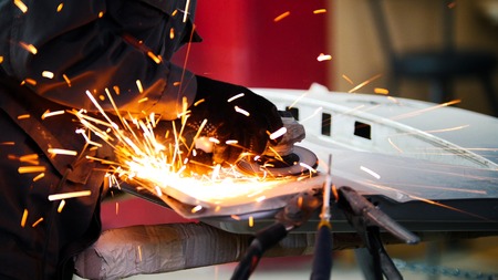 Professional car service - worker grinding metal construction with a circular saw, close upの写真素材