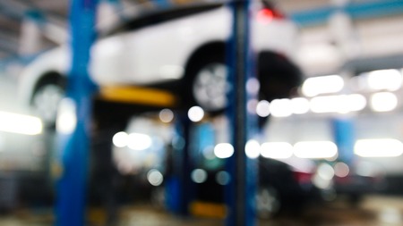 Automobile service - mechanics checking lifted car, de-focused, wide angleの写真素材