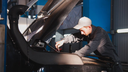 Mechanic male unscrews with a screwdriver in hood of the car for SUV, close up