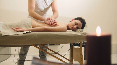 Attractive young woman receiving massage at spa. Relaxation treatment for caucasian modelの写真素材