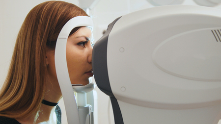 Ophthalmology clinic concept - young attractive female doing checking vision by modern electronic...