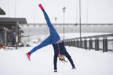 Fitness girl have acrobatic work out fitness at snow winter promenadeの写真素材