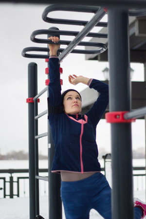 Young sport woman doing strength exercises on work out fitness at snow winter park