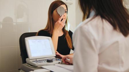 Ophthalmology - white woman checks vision in an ophthalmologist room - short-sighted and squintsの写真素材